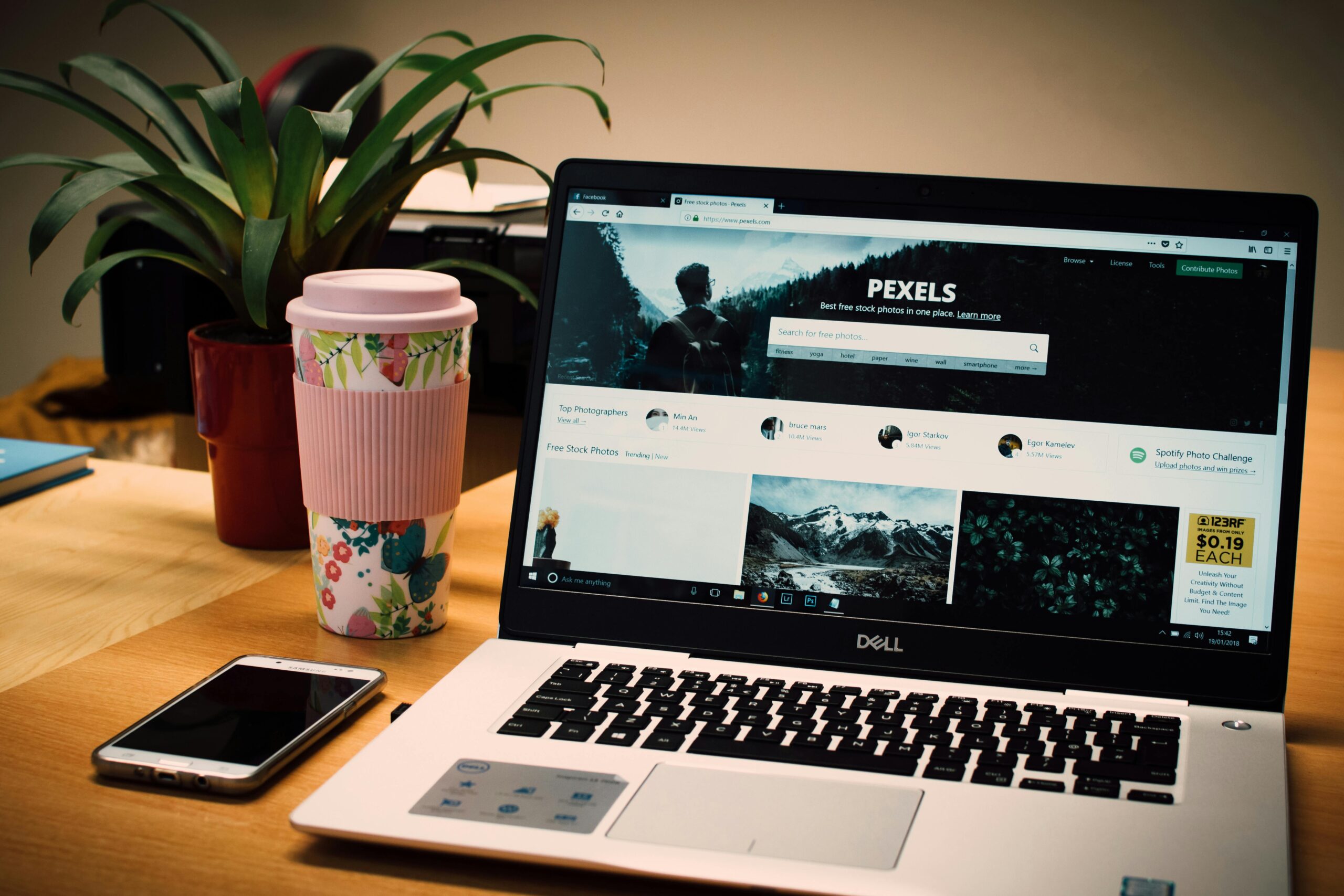Usługi A tidy desk setting with a laptop showing a stock photo website and a smartphone.